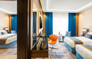 a hotel room with two beds and a chair at Elite Alnokhba - Alkhalidiyyah in Medina +18 photos