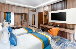 a hotel room with two beds and a flat screen tv at Elite Alnokhba - Alkhalidiyyah in Medina