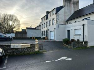 a white house with a parking lot with a car at L'Armateur, Pordic centre in Pordic
