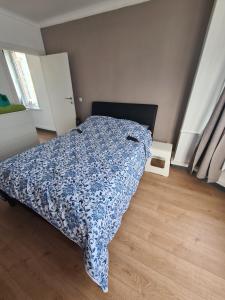 ein Schlafzimmer mit einem Bett mit einer blauen Decke in der Unterkunft Appartement avec parking 50 m de la mer in De Panne