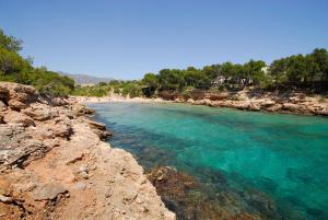 a beach with turquoise water and a rocky shore at VILLA REPOSO in Calafat