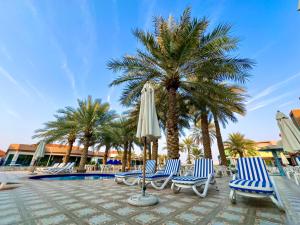 un grupo de sillas y sombrillas junto a una piscina en Royal Residence Hotel Apartments, en Umm Al Quwain