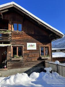 una cabaña de madera con nieve delante en Villa Alberto - gemütliches Häuschen en Ötztal-Bahnhof