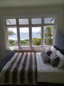 a bedroom with a bed and a large window at Sunrise beach house in Kingsburgh