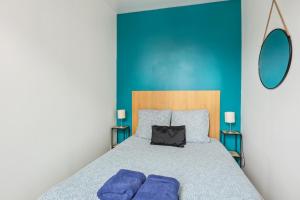 a bedroom with a bed with blue walls and purple pillows at Aux portes de Paris Cozy - Proche Métro L3 L9 in Bagnolet