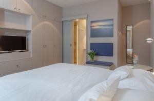 - une chambre avec un grand lit blanc et une télévision dans l'établissement NEU Friesenhof Aenne Haus 4 - Ihr friesisches Zuhause unter Reet in Keitum Sylt, à Keitum