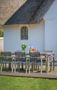 une table et des chaises en bois sur une terrasse dans l'établissement NEU Friesenhof Aenne Haus 4 - Ihr friesisches Zuhause unter Reet in Keitum Sylt, à Keitum