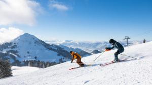 two people are skiing down a snow covered slope at For 2 in Hopfgarten im Brixental
