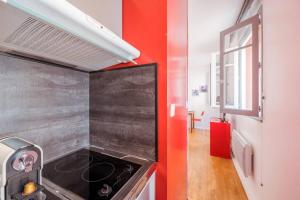 a kitchen with a stove and a red wall at Saint-Sernin - Centre-ville - Calme - WIFI fibre in Toulouse