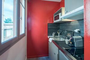 a kitchen with a sink and a red wall at Saint-Sernin - Centre-ville - Calme - WIFI fibre in Toulouse