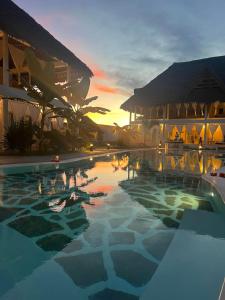 una piscina frente a un edificio con puesta de sol en Weber Zazu - Maisha Resort, en Watamu