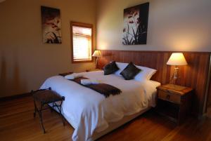 a bedroom with a large bed with white sheets at Stonefly Lodge in Stanley Brook
