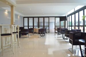 a restaurant with black chairs and tables and windows at Hotel Castellon in Mar del Plata
