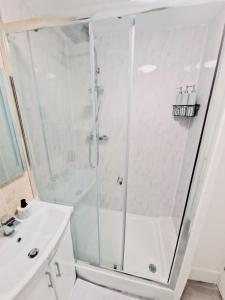 a white bathroom with a shower and a sink at Flat 16 Homedale house in Sutton