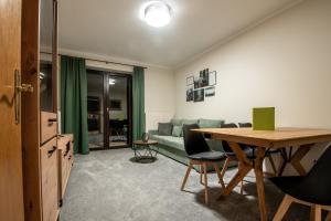 Bergblick Appartements في باد جاستاين: غرفة معيشة مع أريكة خضراء وطاولة