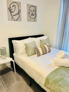Schlafzimmer mit einem Bett mit Kissen und einem Tisch in der Unterkunft High-Spec Skyline Apartment in London - 2 BDR & Balcony in London