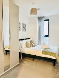 een witte slaapkamer met een bed en een raam bij High-Spec Skyline Apartment in London - 2 BDR & Balcony in Londen