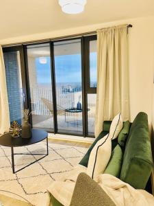 ein Wohnzimmer mit einem grünen Sofa und einem großen Fenster in der Unterkunft High-Spec Skyline Apartment in London - 2 BDR & Balcony in London