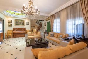 a living room with a couch and a television and a chandelier at Riad Raja in La Soukra