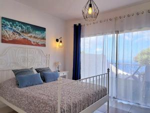 Sunny Tenerife Apartment - ocean views في تاكورونتي: غرفة نوم بسرير ونافذة كبيرة