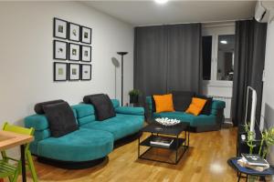 a living room with two blue couches and orange pillows at Sarajevo Tower 24th floor apartment in Sarajevo