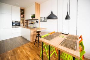 uma cozinha com uma mesa de madeira e cadeiras verdes em Sarajevo Tower 24th floor apartment em Sarajevo