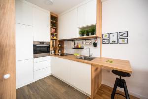 a kitchen with white cabinets and a wooden counter top at Sarajevo Tower 24th floor apartment in Sarajevo