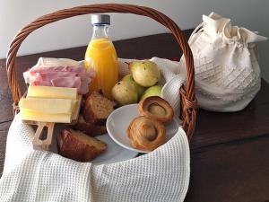 a basket of food with cheese and bread and a bottle of orange juice at Casa dos Correios in Vila Real