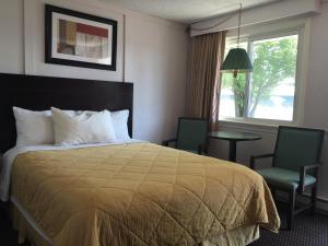 een hotelkamer met een bed en twee stoelen en een raam bij Country Squire Motel in Arnprior