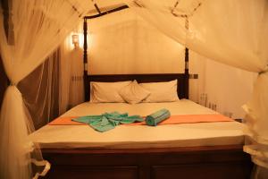 ein Bett mit weißen Vorhängen und einer Schleife darauf in der Unterkunft Chinuka villa in Mirissa