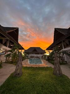 a villa with a swimming pool in front of a sunset at WEBER LUXURY APARTMENTS KENYA - Maisha Resort in Watamu