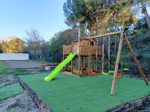 einen Spielplatz mit einer grünen Rutsche auf einem grünen Rasen in der Unterkunft Villa du soleil in Les-Pennes-Mirabeau