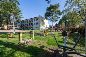 un parque infantil con un edificio al fondo en OW Carbo w sąsiedztwie lasu i jeziora, en Dąbki