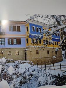 a blue and yellow house in the snow at Ανατολή in Veria