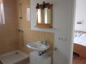 a bathroom with a sink and a shower and a bed at Ferienwohnung Appelbue in Bergenhusen