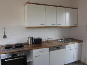 a kitchen with white cabinets and a stove and a sink at Ferienwohnung Appelbue in Bergenhusen