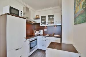 uma cozinha com armários brancos e piso em madeira em Haus Atlantic, FeWo 311 em Döse