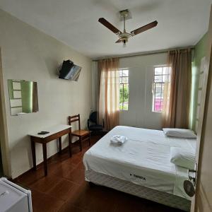a bedroom with a bed and a table and a window at Hotel Turista in Belo Horizonte