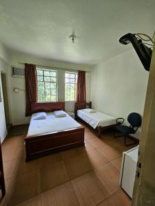 a bedroom with two beds and a chair in it at Hotel Turista in Belo Horizonte
