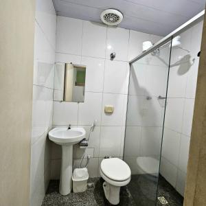 a white bathroom with a toilet and a sink at Hotel Turista in Belo Horizonte