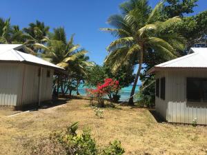 two houses on the beach with palm trees and the ocean at Yawekata Eco Still Bluewater Resort in Naviti Island