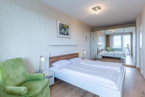 ein Schlafzimmer mit einem weißen Bett und einem grünen Stuhl in der Unterkunft Haus Atlantic, FeWo 305 in Döse