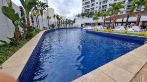 a swimming pool with blue water and palm trees at Apartamento novo ao lado do shopping da ilha in São Luís
