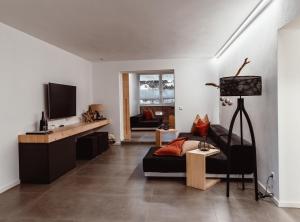 a living room with a black couch and a tv at ALPINE LOFT Martini in Annaberg im Lammertal