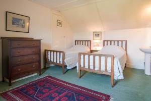 1 dormitorio con 2 camas, vestidor y alfombra en Ardnadrochet Cottage, en Lochdon