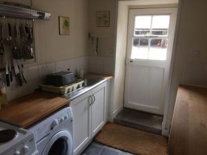 cocina con lavadora y puerta en Ardnadrochet Cottage, en Lochdon 2 fotos más