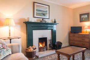 Una sala de estar con chimenea y un sofá. en Ardnadrochet Cottage, en Lochdon
