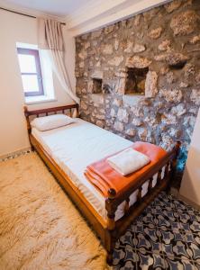 a bed in a room with a stone wall at Mountain Hotels "Balasi's House" in Planitéron