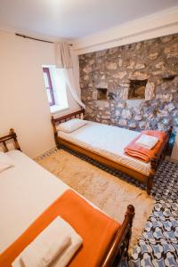 two beds in a room with a stone wall at Mountain Hotels "Balasi's House" in Planitéron