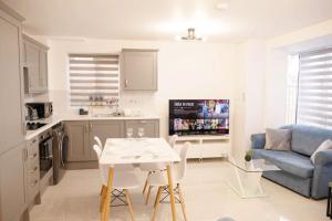 een keuken en een woonkamer met een tafel en een bank bij Walnut Flats-F1, Luxurious 2-Bedroom with Ensuite - Parking, Netflix, WIFI - Close to Oxford, Bicester & Blenheim Palace in Kidlington